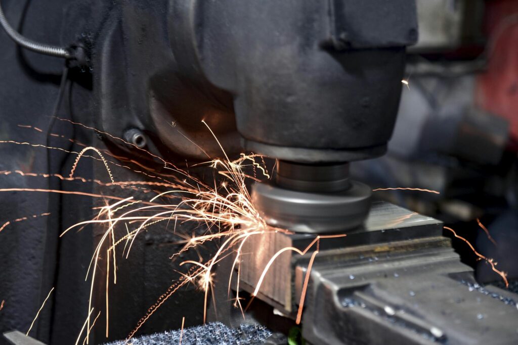 Close-up of a grinding machine in action with sparks flying in an industrial setting.